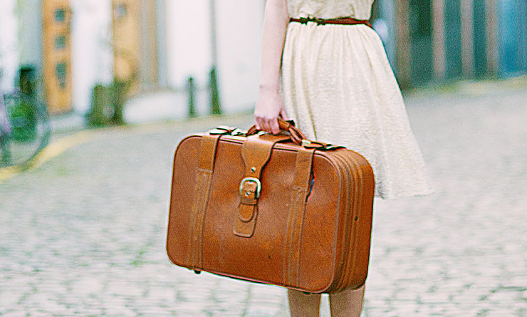大きな旅行バッグを持つスカート姿の女の子の画像