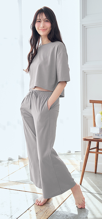 綿100%×接触冷感の天然素材でさらっと涼しく着れるコットン素材のトップスとボトムスの上下セット。特殊な紡績方法の綿糸で、一般的な綿よりもすぐれた吸水速乾性と涼感効果のある、夏にぴったりのルームウェアです。前が少し短く後ろが長めのショート丈トップスとフレアシルエットのロングパンツでトレンドの着こなしが叶います。ボトムスの両サイドにポケットが付いているのもうれしいポイント。薄手で持ち運びもしやすいから、リラックスタイムだけでなくリゾートでもさっと着られるのが便利です。綿100%接触冷感 上下セット